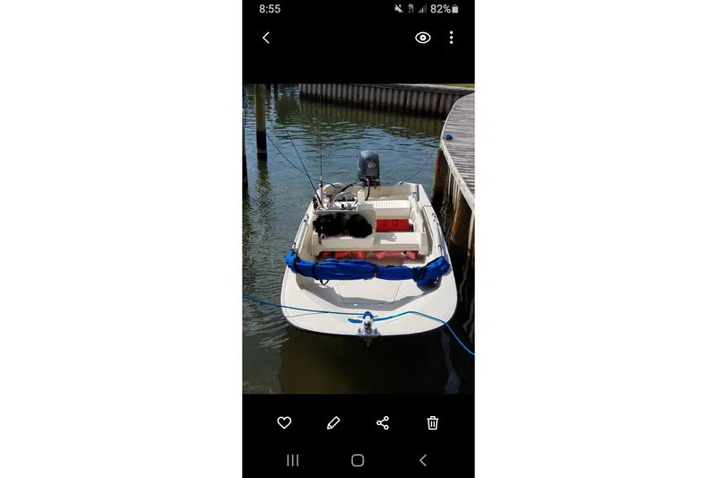 Slide: The Image of 1991 Boston Whaler 15 GLS boat docked, equipped with an outboard motor and fishing gear. - 4