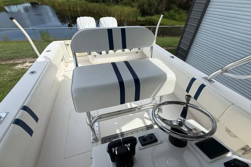 Slide: The Image of 2008 Contender 31 Cuddy boat interior with steering wheel and seating, near a lake. - 11