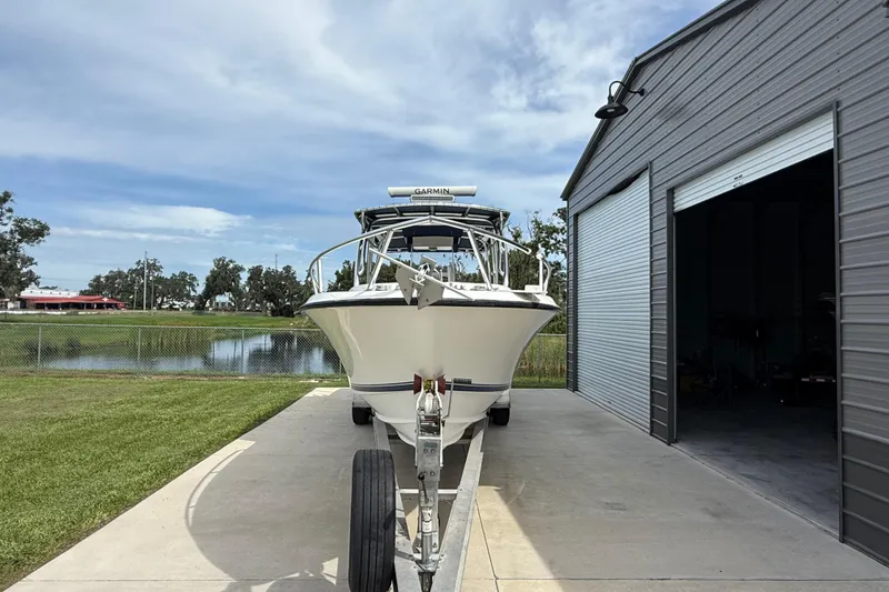 Slide: The Image of 2008 Contender 31 Cuddy boat on trailer near metal building and pond. - 2