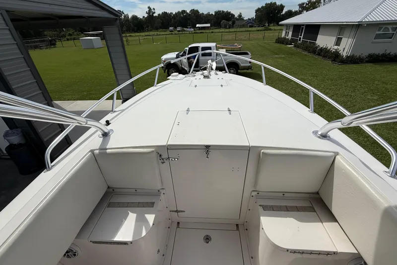 Slide: The Image of 2008 Contender 31 Cuddy boat deck with seating, parked near a house and truck. - 31