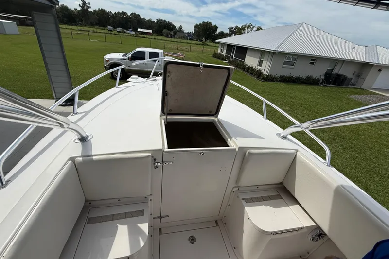Slide: The Image of 2008 Contender 31 Cuddy boat with open storage compartment, parked near a house and truck. - 32