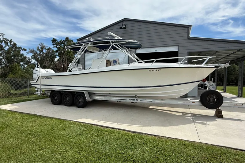 Slide: The Image of 2008 Contender 31 Cuddy boat on trailer, parked near a metal building. - 4