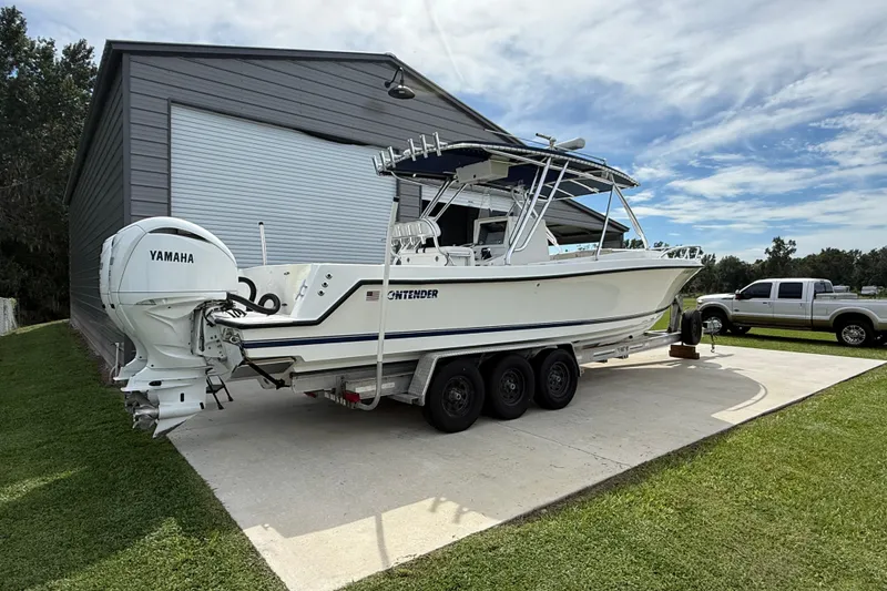 Slide: The Image of 2008 Contender 31 Cuddy boat with Yamaha engines on a trailer near a garage. - 6