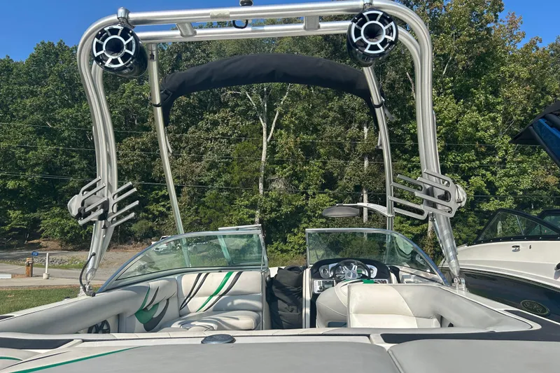 Slide: The Image of 2011 MB F21 Tomcat boat with wakeboard tower and speakers, parked outdoors. - 11