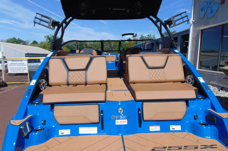 Slide: The Image of 2026 Yamaha Boats 255XD with tan seating and blue exterior, docked outdoors. - 5
