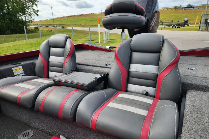 Slide: The Image of 2019 Ranger RT188C boat interior with red and gray seats, parked near a road. - 16