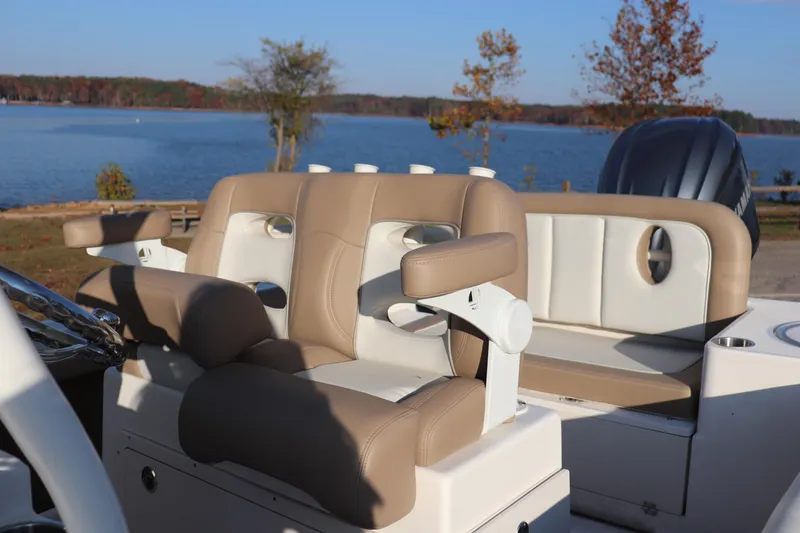 Slide: The Image of 2024 Sea Born LX24 Center Console boat interior with tan seating by a lake. - 8