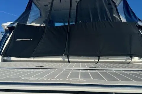 Slide: The Image of 2020 Formula 380 Super Sport Crossover I/O boat with black canopy and deck view. - 8