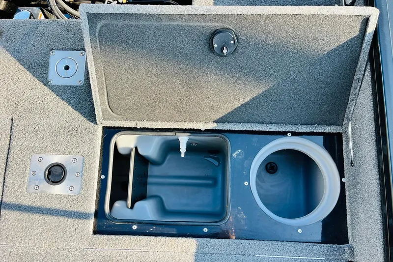 Slide: The Image of 2018 Tracker Targa V-19 Combo boat storage compartment with open lid and cup holder. - 42