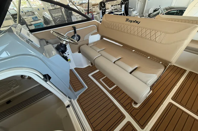Slide: The Image of 2025 Bayliner Trophy T22SC boat interior with beige seating and wood-patterned flooring. - 12