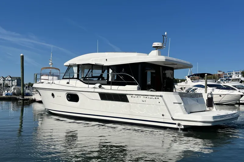 Slide: The Image of 2026 Beneteau 41 Swift Trawler Sedan docked in a marina under clear blue skies. - 12