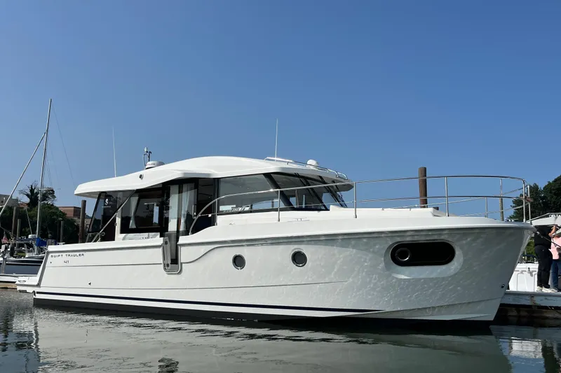 Slide: The Image of 2026 Beneteau 41 Swift Trawler Sedan docked in a marina under clear blue skies. - 3