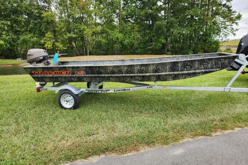 The Image of 2026 Tracker Grizzly 15 Jon boat on trailer, parked on grass near trees. - 0