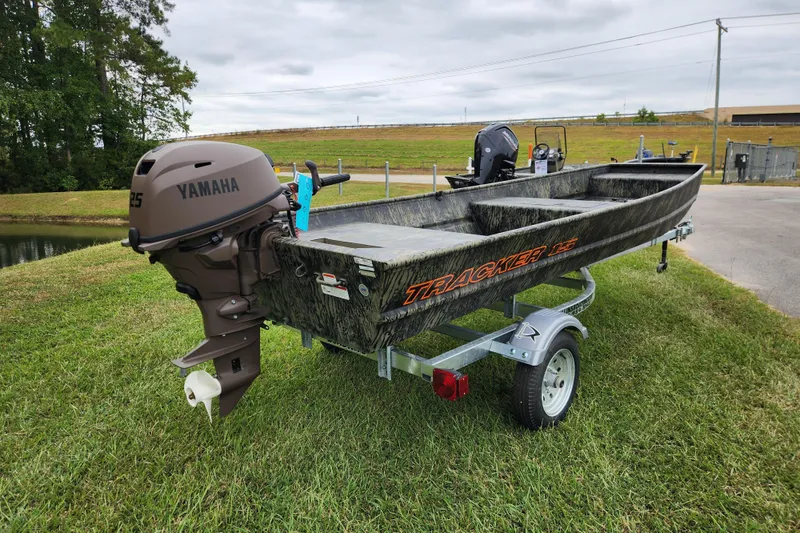 Slide: The Image of 2026 Tracker Grizzly 15 Jon boat with Yamaha motor on trailer, parked on grass. - 2