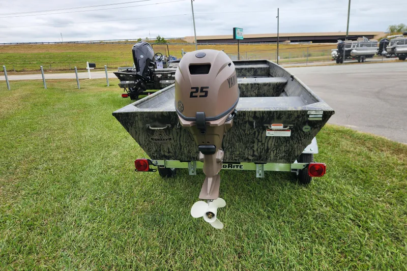 Slide: The Image of 2026 Tracker Grizzly 15 Jon boat with outboard motor on trailer, parked on grass. - 4