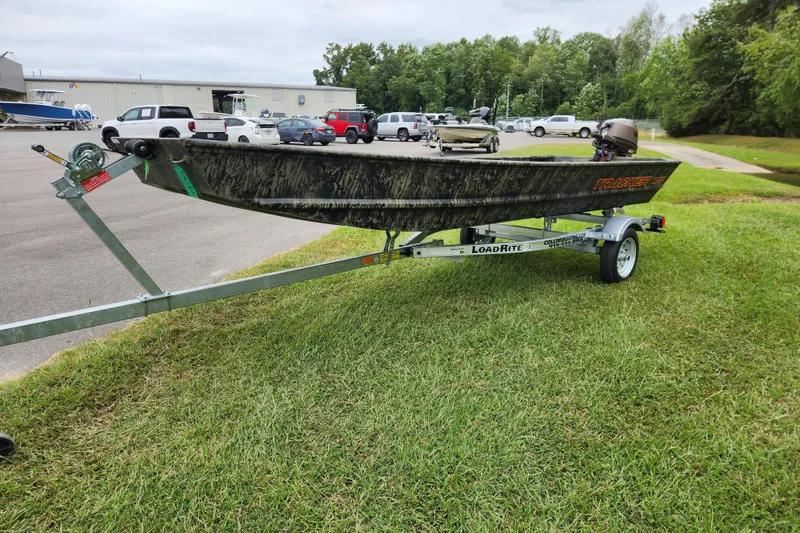 Slide: The Image of 2026 Tracker Grizzly 15 Jon boat on Load Rite trailer, parked on grass. - 8