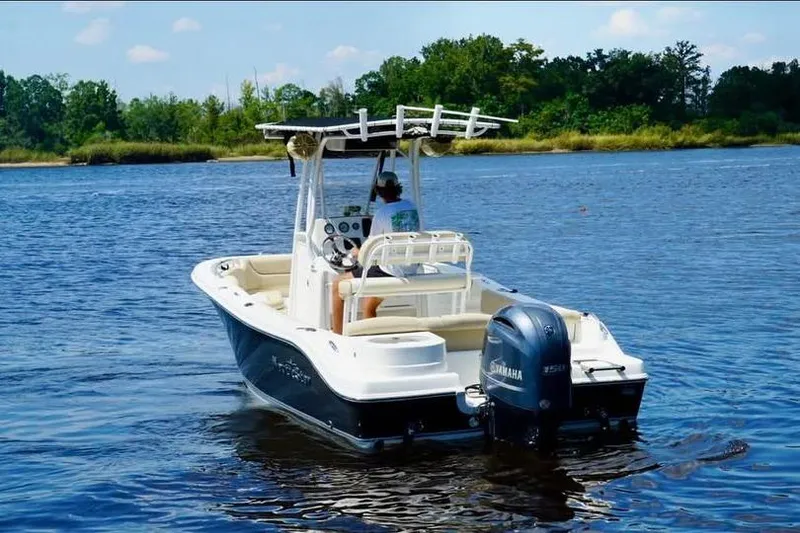 Slide: The Image of 2018 NauticStar 2102 Legacy boat on a calm lake with lush green shoreline. - 3