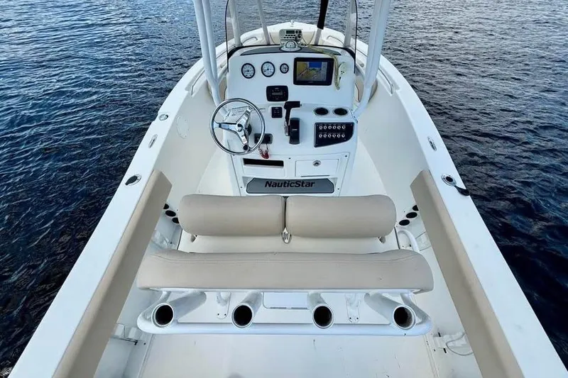 Slide: The Image of 2018 NauticStar 2102 Legacy boat interior with steering console and seating on water. - 6