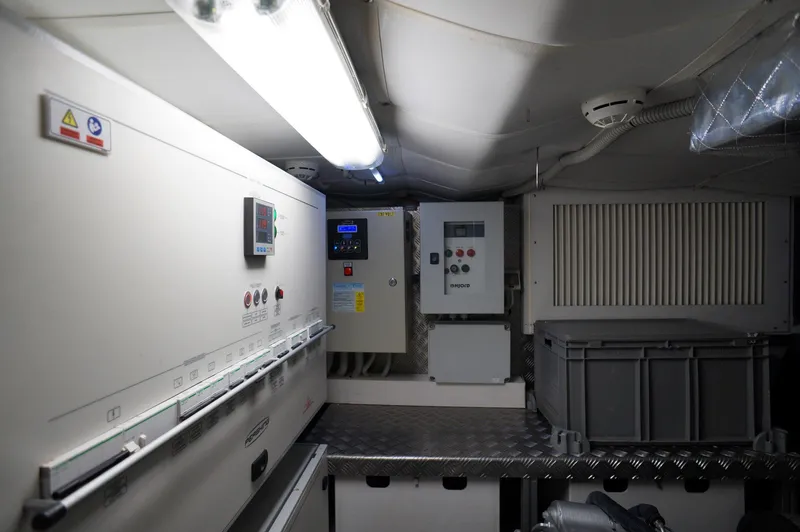 Slide: The Image of Engine room of a 2016 Pershing 70 yacht, featuring control panels and storage. - 32