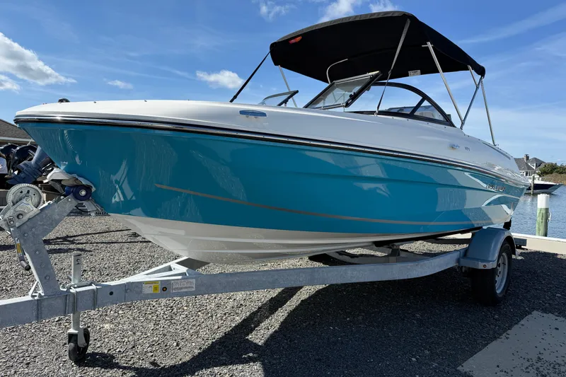Slide: The Image of 2025 Bayliner VR4 Bowrider OB on trailer, blue and white design, sunny day. - 2