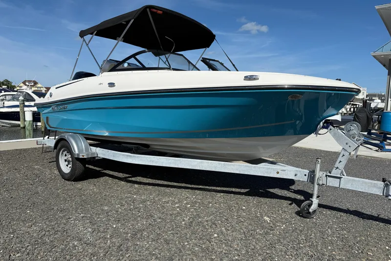 Slide: The Image of 2025 Bayliner VR4 Bowrider OB on trailer, blue and white, parked outdoors. - 8
