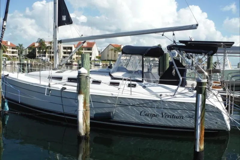 The Image of 2009 Hunter 38 sailboat on stands, white hull, red bottom, outdoor storage area. - 0