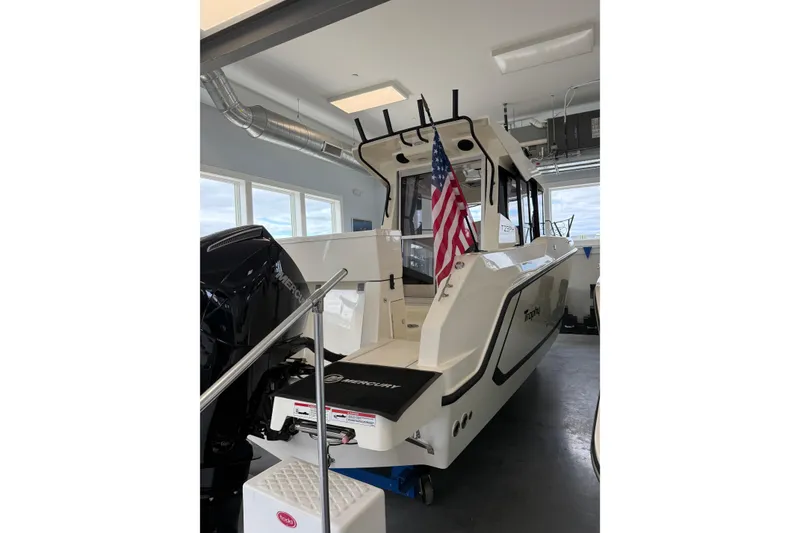 Slide: The Image of 2025 Bayliner Trophy T23 Pilothouse boat in showroom, rear view with Mercury engine. - 2