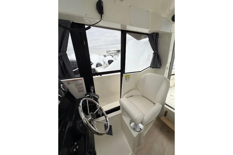 Slide: The Image of Interior of 2025 Bayliner Trophy T23 Pilothouse, featuring helm and comfortable seating. - 20