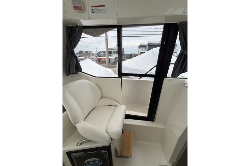 Slide: The Image of Interior of 2025 Bayliner Trophy T23 Pilothouse with white seating and large windows. - 21