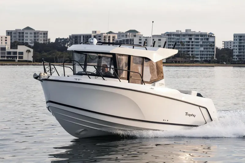 Slide: The Image of Manufacturer Provided Image: 2025 Bayliner Trophy T23 Pilothouse boat cruising on calm water near urban skyline. - 23