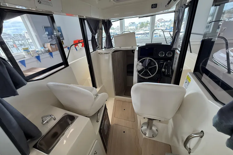 Slide: The Image of 2025 Bayliner Trophy T23 Pilothouse interior with compact fridge and storage compartments. - 6