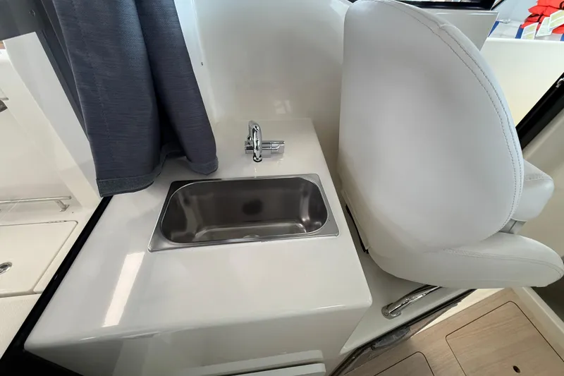 Slide: The Image of 2025 Bayliner Trophy T23 Pilothouse helm with steering wheel, controls, and Simrad display. - 8