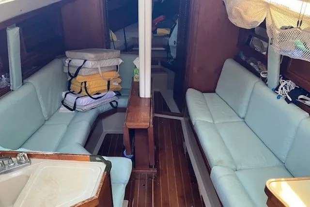 Slide: The Image of Interior of 1990 C&C 30-2 sailboat with light blue seating and wooden flooring. - 14