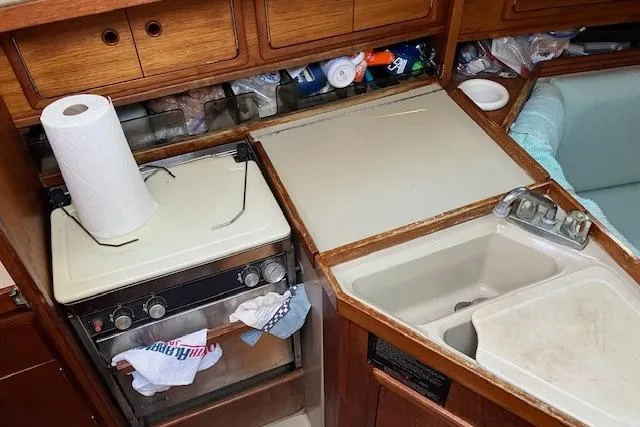 Slide: The Image of 1990 C&C 30-2 yacht kitchen with stove, sink, and storage cabinets. - 16