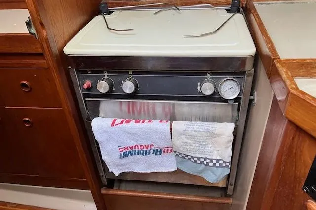 Slide: The Image of 1990 C&C 30-2 yacht interior with vintage stove and hanging towels. - 17