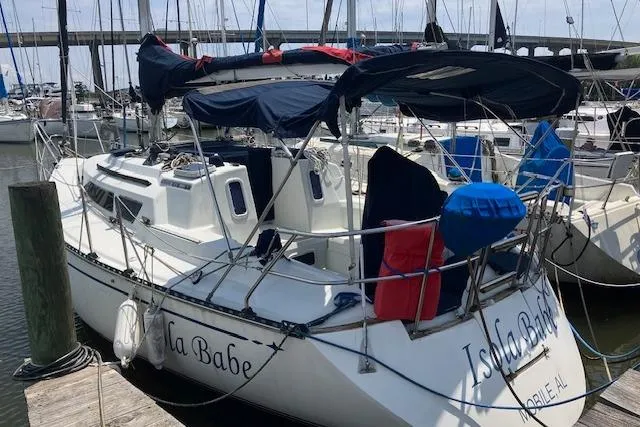 Slide: The Image of 1990 C&C 30-2 sailboat docked at marina, featuring blue and red covers. - 2