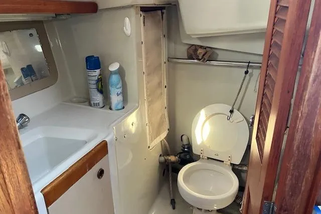 Slide: The Image of 1990 C&C 30-2 sailboat bathroom with sink, toilet, and cleaning supplies. - 21