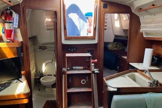 Slide: The Image of Interior of a 1990 C&C 30-2 sailboat, featuring a compact kitchen and bathroom. - 29