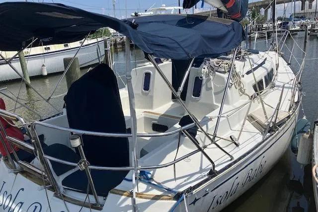 Slide: The Image of 1990 C&C 30-2 sailboat docked at marina with blue canopy and railing. - 3