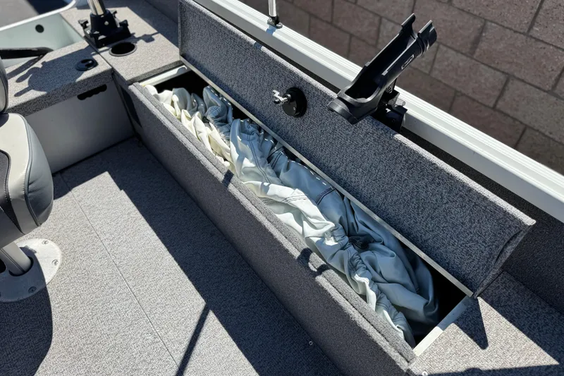 Slide: The Image of 2020 Alumacraft Escape 165 SC boat storage compartment with fabric cover and rod holder. - 16