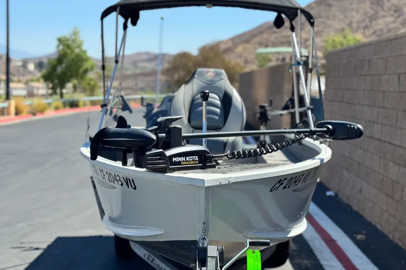 Slide: The Image of 2020 Alumacraft Escape 165 SC boat with Minn Kota motor, parked outdoors. - 2