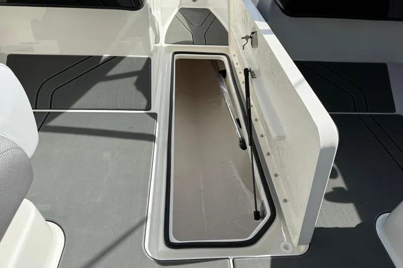Slide: The Image of 2025 Bayliner V20 boat storage compartment with open hatch and gray flooring. - 12