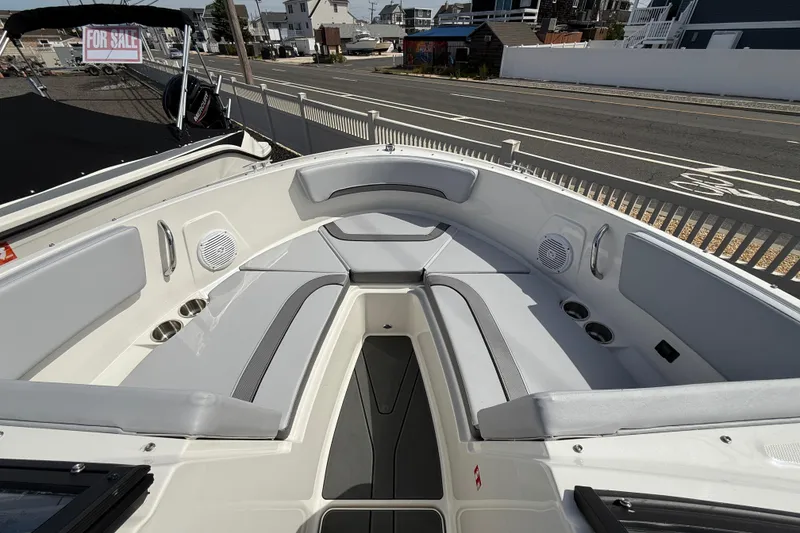 Slide: The Image of 2025 Bayliner V20 boat interior with gray seating, cup holders, and speakers, parked near a road. - 13