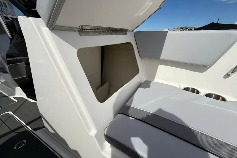 Slide: The Image of 2025 Bayliner V20 boat interior storage compartment with cushioned seating and cup holders. - 15