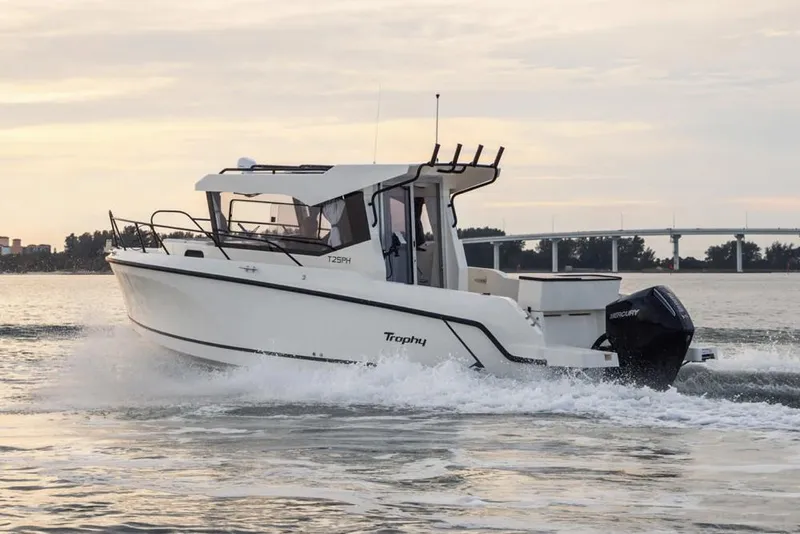 Slide: The Image of Manufacturer Provided Image: 2025 Bayliner Trophy T25 Pilothouse boat cruising on water at sunset. - 1