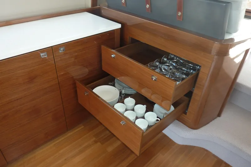 Slide: The Image of Wooden yacht kitchen with open drawers displaying dishes and glassware, Princess 52, 2017 model. - 22