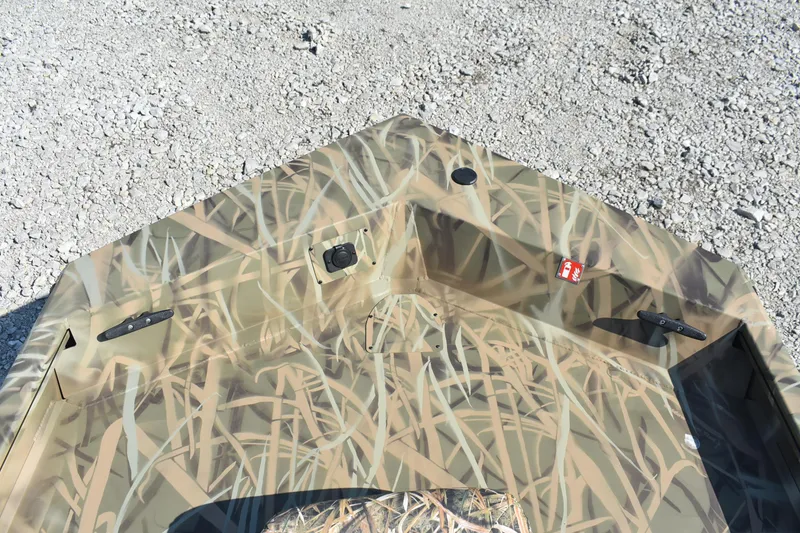 Slide: The Image of 2026 Lowe Roughneck 1860 boat with camouflage design on gravel surface. - 10