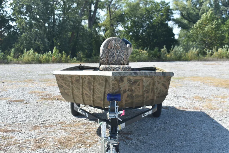 Slide: The Image of 2026 Lowe Roughneck 1860 boat on trailer, camo design, parked outdoors. - 2