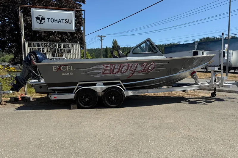 The Image of 2025 Excel Buoy 10 boat on trailer, parked near Tohatsu sign. - 1