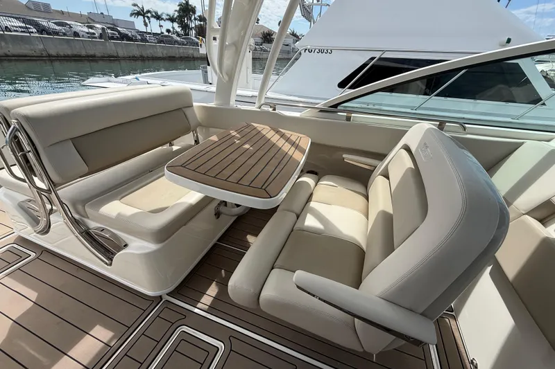 Slide: The Image of 2023 Boston Whaler 320 Vantage interior with beige seating and wooden table. - 14